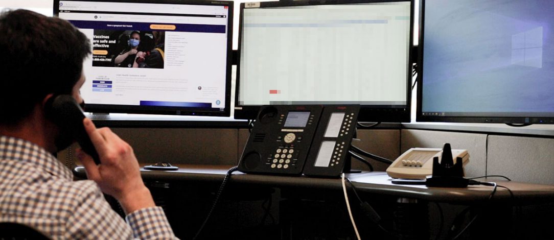 Photo of a man on the phone with the coronavirus website on his computer screen