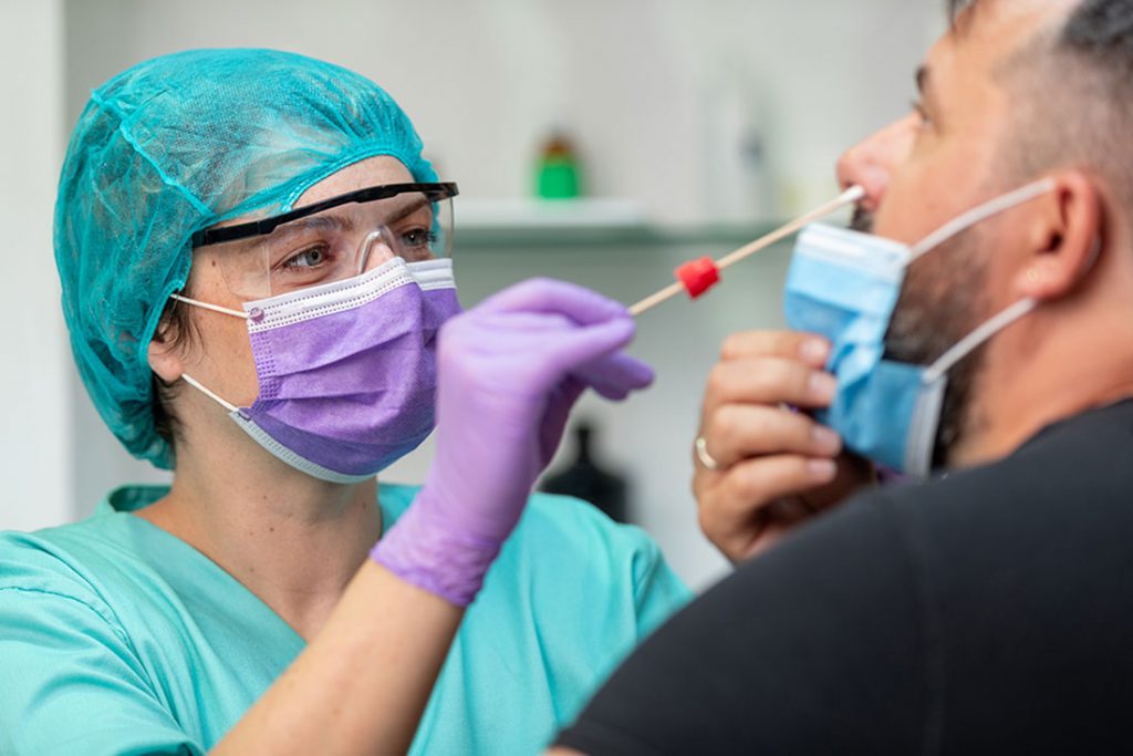 a nurse administers a nasal swab test to a man