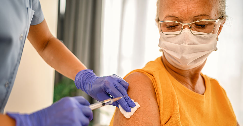 Photo of an elderly woman receiving a vaccination in her arm